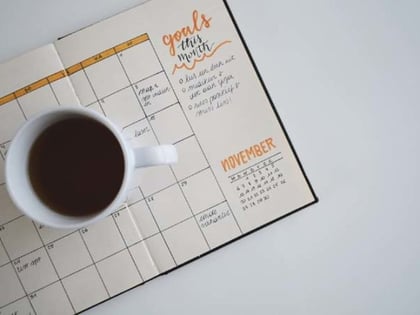 Blick von oben auf ein Kalender Journal mit einer Tasse Kaffee