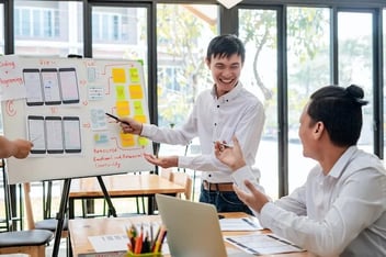 Two UX specialists plan an SEO strategy for a website on a board.
